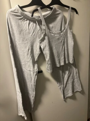 Grå ribbade mjukisbyxor med snörning - Säljer ett par grå mjukisbyxor med ribbad struktur och snörning i midjan. Byxorna har en avslappnad passform och är gjorda i mjukt bomullsmaterial. Perfekta för chill dagar hemma eller när du vill vara extra bekväm.