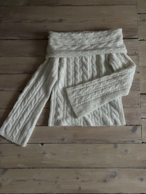 Vit offshoulder stickad tröja - Superfin vit stickad tröja med bred offshoulder-krage och kabelstickat mönster. Tröjan har vida ärmar och är inte genomskinlig. Den är från New Yorker i storlek S💕Endast använd en gång!