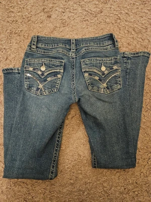 Blå jeans med paljettdetaljer Gina Tricot - Snygga low-waist bootcut blå jeans från Gina Tricot i storlek 152. Jeansen har klassisk femficksdesign och coola bakfickor med broderade mönster och paljetter. Använda max tre gånger, och därför i väldigt bra skick och priset. Jättesnygga, säljer då jag redan har massa andra jeans och dessa glöms bort i garderoben. Nypris 399 kr.