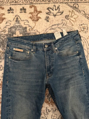 Calvin Klein Slim Taper jeans blå W29 L32 - Säljer ett par blå Calvin Klein jeans i modellen Slim Taper. Jeansen har klassisk femficksdesign, snyggt tvättad denim och smal passform som smalnar av nedtill W29 L32