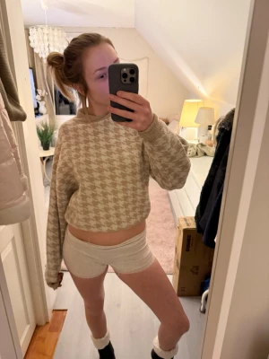 Beige stickad tröja med hundtandsmönster H&M - Supermysig beige stickad tröja från H&M i storlek XS. Tröjan har ett klassiskt hundtandsmönster i beige och vitt, ribbade muddar och avslappnad passform. Perfekt för höst och vinter när man vill vara både snygg och bekväm.