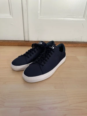 J.Lindeberg Sneakers - Blå J.Lindeberg sneakers i storlek 42 TTS. Mycket gott skick, använda fåtal gånger. Låda medföljer.