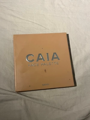 CAIA Face Palette Sassy - Snygg ansiktspalett från CAIA i färgen Sassy med fyra olika puder: contour i beige, blush i rosa, bronzer i varm brun och highlighter i skimrande champagne. Perfekt för att skapa en fräsch och glowig look. Kommer i en stilren fyrkantig förpackning med spegel.