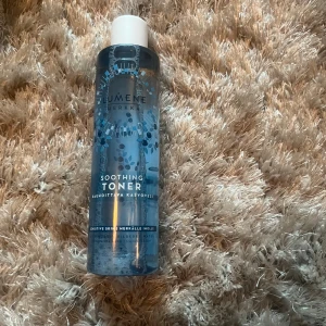 Lumene Soothing Toner 250ml - Fräsch och lugnande ansiktsvatten från Lumene i en genomskinlig blå plastflaska med vitt lock. Passar känslig hud och ger en mjuk och återfuktad känsla. Perfekt för att balansera huden efter rengöring.