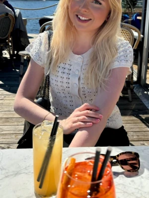 Vit stickad blus/kofta - Supersöt vit stickad kofta med korta ärmar och rund hals. Toppen har dekorativa knappar framtill och ett hålmönster som ger en luftig känsla. Perfekt till vår och sommar för en fräsch och trendig look🍸🐚🌊 