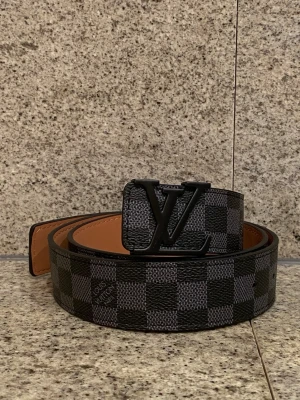 Rutigt bälte med svart emblem  - Helt nytt