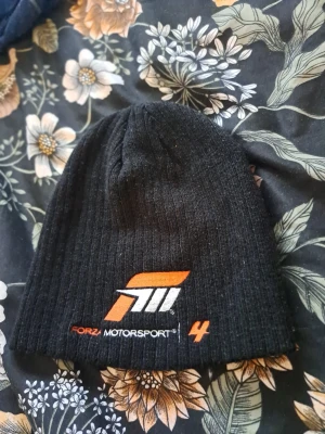 Forza Motorsport svart mössa - Svart mössa med Forza Motorsport logotyp. Är i gott skick & väldigt sparsamt använd.   Skickas via posten men köpare står för frakten. Vid övriga frågor skicka gärna meddelande.  Lämnar självklart god omdömen om köparen gör det.  Kolla in gärna på mina andra annonser!