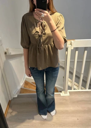 Helt Ny Lager 157 Blus - Storlek S - Letar du efter en snygg och mångsidig blus som passar till allt? Då har du hittat rätt! Denna bruna/khaki kortärmade blus från Lager 157 är helt ny med etikett kvar. Den har en trendig knytning där fram som ger en avslappnad men ändå chic look. Perfekt för både vardag och fest!  👕Storlek: S 🏷️Skick: Helt ny med etikett 🎨Färg: Brun/khaki (enkel att matcha) 🧵Material: 99% Polyester, 1% Elastan  Skriv gärna om du har några frågor. Djur och rökfritt hem, pris kan diskuteras!💖
