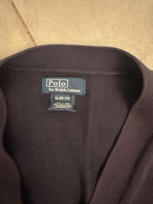 Marinblå kofta från Polo Ralph Lauren - Snygg marinblå  kofta från Polo Ralph Lauren i storlek S-m. Koftan är stickad och har en klassisk, enkel design med ribbade kanter. Perfekt för lager-på-lager och passar dig som gillar stilrena plagg med premiumkänsla.