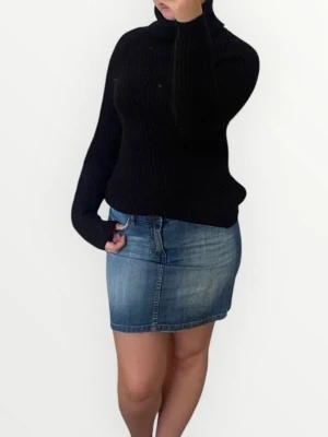 Svart stickad polotröja - Mysig svart stickad polotröja med lång ärm och hög krage. Den är inte tunn utan snarare åt de tjockare hållet. Tröjan har en klassisk, lite loose passform och är perfekt för kyligare dagar. Enkel att matcha med jeans eller kjol för en stilren look. 