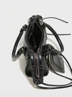 Oanvänd Svart handväska i skinn med dragkedjor - Cool svart handväska i skinn med flera dragkedjor, dubbla handtag. Väskan har dekorativa remmar och ett fack framtill samt en hängande tag. Perfekt storlek för det viktigaste och ger en edgy vibe till din outfit. INGEN KORTHÅLLARE KOMMER MED TYVÄRR OCH INGET AXELBAND❤️❤️❤️❤️❤️