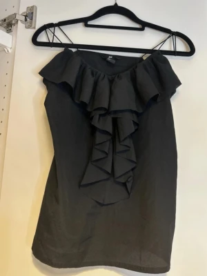 Svart volangtopp - Jättefin svart topp med volangdetaljer. Passar perfekt till fest.