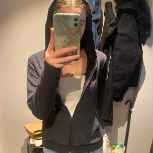 Marinblå hoodie med dragkedja - Mysig marinblå hoodie med dragkedja framtill och huva. Tröjan har långa ärmar, två fickor och är tillverkad i ett mjukt fleecematerial. Perfekt för chill dagar eller när du vill vara extra bekväm.
