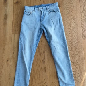 Ljusblå skinny jeans från Weekday - Säljer ett par ljusblå skinny jeans från Weekday med klassisk femficksdesign och läderpatch bak i midjan. Jeansen har smal passform och är tillverkade i mjukt denimtyg. Perfekta för en clean och avslappnad look.