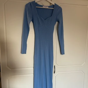 Ljusblå ribbad långklänning från Adoore Roma - Supersnygg ljusblå långklänning från Adoore med ribbad struktur, lång ärm och v-ringad urringning framtill. Klänningen har figurnära passform och en liten slits bak! Den passar storlekarna 32-36/38 eftersom den är såpass stretchig🩵