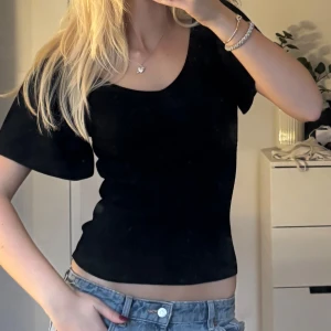 Fest topp ONLY - Virala Only fest toppen. Säljer en svart ribbad topp med v-ringning och korta ärmar. Toppen har en tight passform och är i ett stretchigt material som sitter snyggt på kroppen. Perfekt att matcha med jeans eller kjol för en clean look.