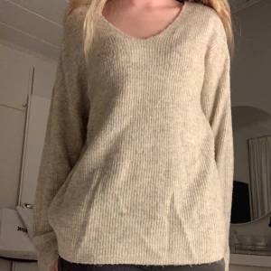 Beige ribbad stickad tröja v-ringad - Mysig beige stickad tröja med v-ringning och ribbad struktur. Tröjan har en loose passform och långa ärmar, perfekt för lager på lager. Kommer inte till användning hos mig!😊