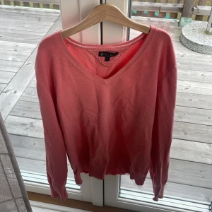 Rosa v-ringad tröja från Key West - Säljer en rosa v-ringad tröja från Key West i storlek L men sitter som S. Tröjan har långa ärmar och är tillverkad i mjukt bomullsmaterial. Perfekt för dig som gillar en enkel men snygg stil med en poppig färg.