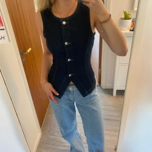 Mörkblå jeanstopp med knappar - Säljer en mörkblå, figursydd jeanstopp! Stretschigt material men ganska tjockt så den är väldigt bekväm även om den sitter tight. Aldrig använd men lappen är tyvärr avtagen. 