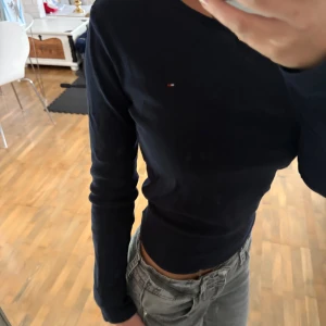 Mörkblå långärmad tröja Tommy Hilfiger - Säljer en mörkblå långärmad tröja från Tommy Hilfiger med klassisk rund halsringning och liten broderad logga på bröstet. Tröjan är i mjuk bomull och har en slim passform som sitter snyggt på kroppen.