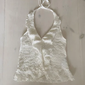 Vit volang halterneck topp från Nelly - Supersöt vit halterneck topp från Nelly i storlek XS🤍 Toppen har volangdetaljer längs v-ringningen och nertill. Aldrig använd då den tyvärr kändes för stor för mig.