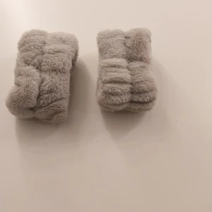 Grå fluffiga handledsvärmare - Supermjuka och fluffiga handledsvärmare i ljusgrå färg. De är tillverkade i ett pälsliknande material som känns riktigt gosigt mot huden. Perfekta för att hålla handlederna varma under kyliga dagar. Säljs i par.