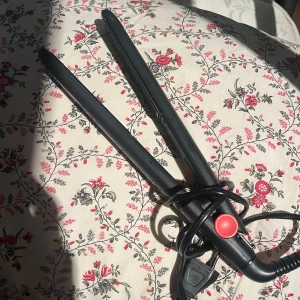 Svart plattång från Remington - Säljer en svart plattång från Remington med smala, släta plattor och en röd knapp. Perfekt för att styla håret rakt eller skapa lockar. Sladden är lång och flexibel, vilket gör den enkel att använda. Klassisk design i tåligt material.