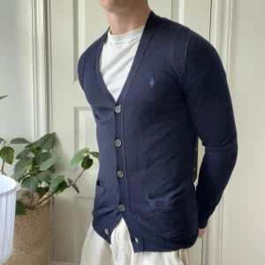 Ralph Lauren cardigan merino wool - Ralph Lauren cardigan merino wool slim fit, inga större defekter. Någon lös tråd här och där men inget större. Modellen är 180,75 kg och bär S vilket är litet på honom. 🫶