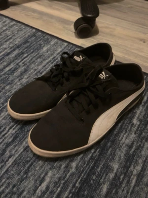 Svarta Puma sneakers med vit logo - Basic svarta sneakers från Puma med vit sidologga och svarta skosnören. Skorna är köpta till en vän använda kanske 2-3 gånger och kommer inte till användning så typ helt nya men man kan se på undersidan som på bilden att dom är lite använda men de går nog att ta bort.