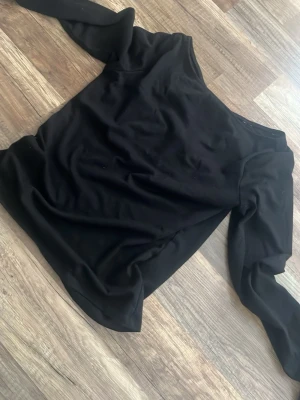 Svart topp - Snygg svart topp med långa ärmar. Tunn och stretchig, perfekt för att skapa en cool och trendig look. Passar till både jeans och kjol för en stilren outfit.