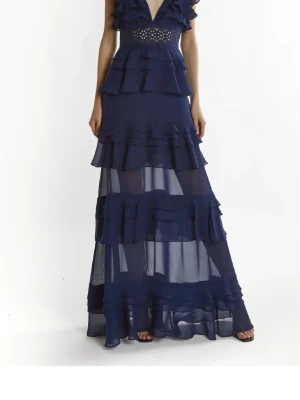 Klänning - Säljer en elegant mörkblå maxiklänning med djup v-ringning, breda axelband och flera lager volanger. Perfekt nu till balen! Köpte för 2300kr säljer för 1000kr storlek xs-s❤️