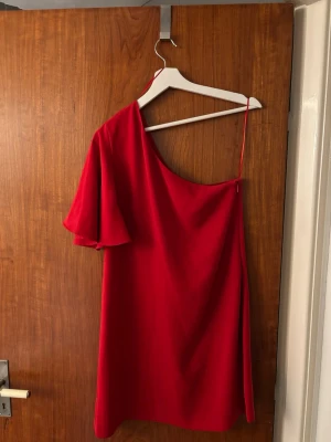 Röd oneshoulder klänning - Snygg röd oneshoulder klänning med en ärm från Mango. Ser exakt ut som den gula från Zara!Klänningen är i superbra skick. 