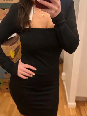 Svart långärmad klänning  - Snygg svart långärmad klänning från NA-KD med figurnära passform och fyrkantig urringning och axelvaddar. Aldrig använd med lappen kvar