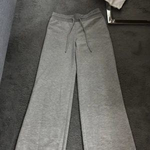 Grå mjukisbyxor med dragsko - Säljer ett par grå mjukisbyxor med ben. Byxorna har en avslappnad passform och är tillverkade i mjukt material som passar perfekt för chill dagar. Enkla att matcha med hoodie eller t-shirt.