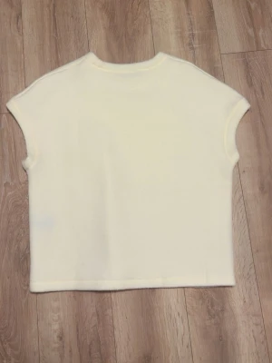 Vit ärmlös topp i bomull - En stilren vit topp med ärmlös design och rund halsringning. Tillverkad i mjuk bomull, perfekt för en enkel och clean look. Passar till många olika outfits och är lätt att matcha.