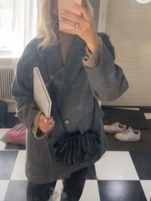 Grå oversized kappa med knappar - Stilren grå kappa i oversized modell med dubbelknäppning framtill och två fickor.