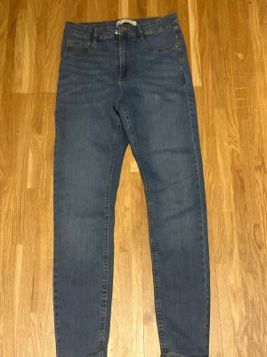 Blå Molly jeans med smal passform - Säljer ett par klassiska blå Molly jeans från Gina Tricot. Jeansen har smal passform, normal midja och fem fickor. Materialet är stretchigt denim som sitter snyggt och bekvämt. Perfekta för dig som gillar en enkel och stilren look.