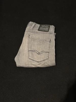 Ljusgrå jeans från Replay - Snygga ljusgrå jeans från Replay med klassisk femficksdesign och raka ben. Jeansen har en diskret logga på bakfickan och är tillverkade i ett mjukt denimtyg som ger en skön känsla. Perfekta för dig som gillar stilrena och moderna jeans.