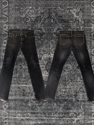 APC petit new standard - Snygga svarta slim fit jeans med diskreta slitningar och klassiska fem fickor. Sköna fades och vit contrast stitching. Jeansen har en låg midja och raka ben, perfekta för en cool och avslappnad stil. 