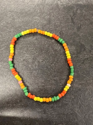 Färgglatt pärlarmband storlek L - Ett handgjort armband med pärlor i grönt, gult, orange. 