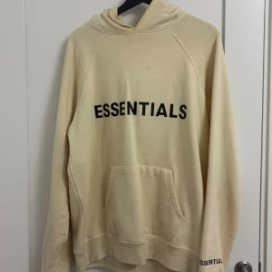 🏷 Essentials Hoodie (Cream) – Storlek M (Oversized Fit) - Beige/cream Essentials Fear of God-hoodie i oversize fit. Klassisk design med logga fram och bak. Storlek: M (oversized)