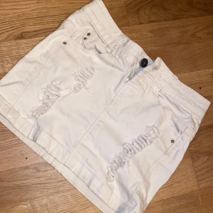 Vit kortkjol från Uniq DNM, strl 34 - Säljer en vit jeanskjol från Uniq DNM i storlek 34. Kjolen är kort och har slitna detaljer framtill, klassiska jeansfickor med nitar och knappstängning. Perfekt för dig som gillar en edgy och avslappnad stil. Den super gullig men kommer inte till användning har typ inga defekter men kom privat 🫶🏻