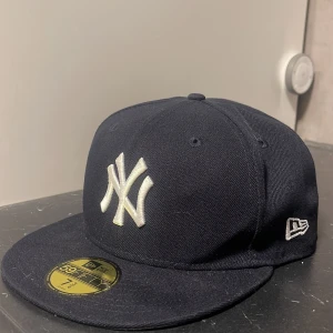 New Era Yankees svart keps 59FIFTY - Säljer en klassisk svart New Era 59FIFTY keps med New York Yankees-logga broderad i vitt framtill. Kepsen är i modellen fitted och har MLB-logga bak. Tillverkad i 100% polyester och har en snygg, stilren look.