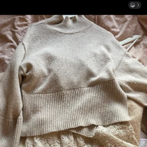 Beige stickad polotröja - SKRIV FÖR FLER BILDER!!! Mysig beige stickad polotröja med ribbad hög hals och bred ribbad kant nedtill. Tröjan har lång ärm och en avslappnad passform, perfekt för kyliga dagar. Enkel att matcha med både jeans och kjol.