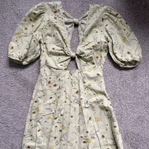 Somrig klänning med puffärm - 🤍Superfin ljusgrön kortklänning med blommigt mönster, puffärmar och knytning framtill. Klänningen har cut-out-detaljer och v-ringning 🤍