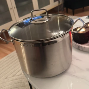 Master Rostfri Gryta 8L - Stor gryta i rostfritt stål 18/10 med lock, rymmer upp till 8 liter. Passar alla typer av spisar: gas, el, keramik, halogen och induktion. Tål diskmaskin. Grytan är i mycket gott skick utan synligt slitage eller defekter.