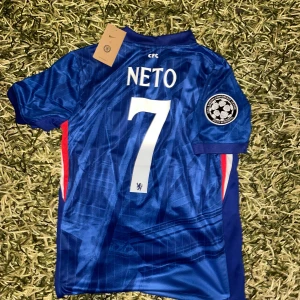Chelsea FC 25/26 hemma fotbollströja  - Chelsea FC fotbollströja med Dri-FIT material, korta ärmar och klassisk krage. Tröjan är blå med subtila ränder, har klubbmärke och Nike-logga på bröstet samt patch på ärmen. Namn och nummer 'NETO 7' på ryggen. Perfekt för fans!
