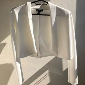 Vit croppad kavaj från Boohoo - Elegant vit  kavaj med en kortare modell och öppen front. Aldrig använd endast testad. 