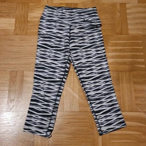 Nike Dri-Fit leggings XS zebra - Nike Dri-Fit leggings i storlek XS med svartvitt zebramönster. 3/4 längd på byxbenen. Högmidjade och tillverkade i ett stretchigt syntetmaterial som andas, perfekta för träning. Snyggt mönster och skön passform för dig som gillar att sticka ut.