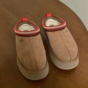 UGG tasman skor platform strl.38 - Säljer ett par beige slip-on skor från UGG tasman med platform strl 38, knappt använda som nya. 